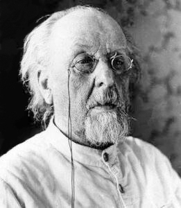 Greyscale photograph of Konstantin Tsiolkovsky, an old man with a white goatee wearing a pair of glasses and wearing a white button-up shirt.