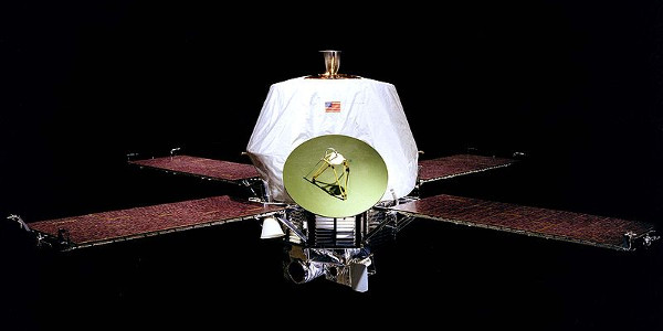 A photograph of the Mariner 9 space probe against a black background. The probe has a cross of four solar panels, a large antenna dish and a white plastic sheet covering the main instruments.