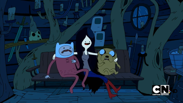 Marceline the Vampire Queen, a thin teenaged girl with grey skin and two red dots on ner neck, slides in between Finn and Jake inside their treehouse.