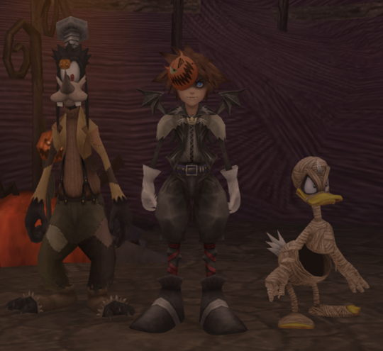 Sora, Donald and Goofy in their halloween outfits. Donald wears bandages, Sora is in a kind of black leather outfit with tiny batwings and a small pumpkin mask at the corner of his face, and Goofy is Frankenstein's monster with a large bolt on his head.