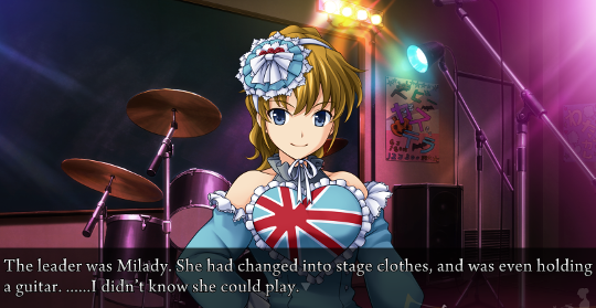 Jessica standing on stage in front of a drum set, wearing a pale blue off-the-shoulder dress with a large heart shape emblazed on the front and lots of lace, and a complicated hair decoration. The heart shape has four red lines that all cross at a point, with white outlines, much like the Union Flag of the United Kingdom. The narration says ‘The leader was Milady. She had changed into stage clothes, and was even holding a guitar. ……I didn’t know she could play.’
